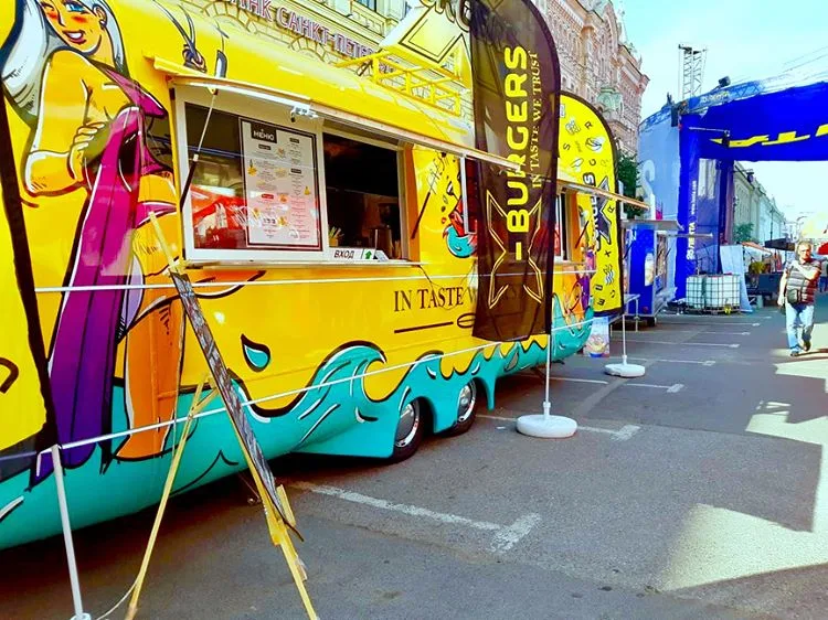 Illustrated yellow and turquoise MobiEdge 8 food trailer serving at an outdoor event