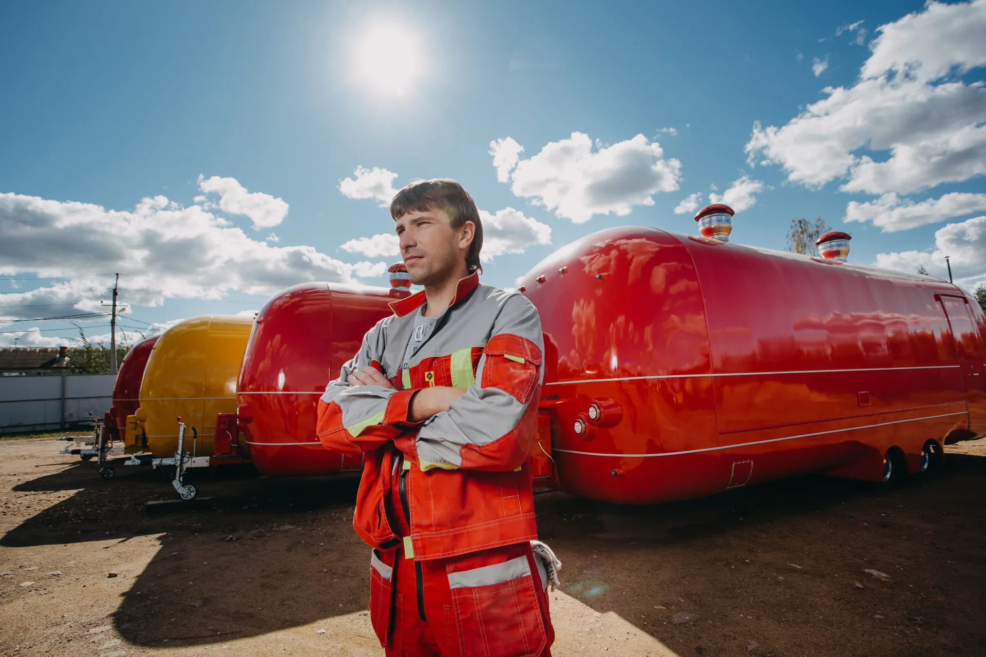 MOBITRUCK production worker standing in front of completed red and yellow trailer shells