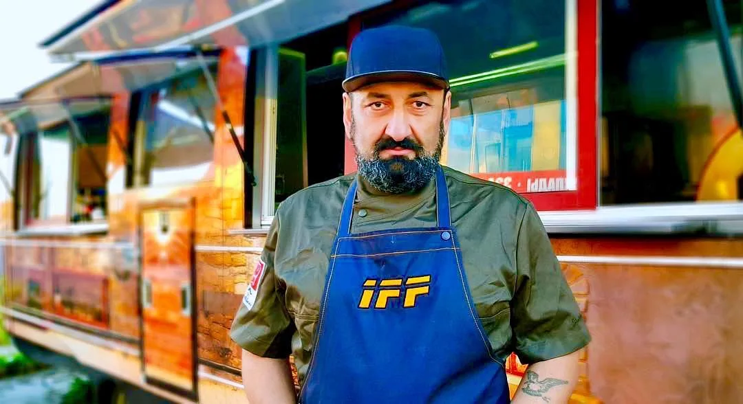 Chef standing at the service windows of a wood-finished mobile food trailer