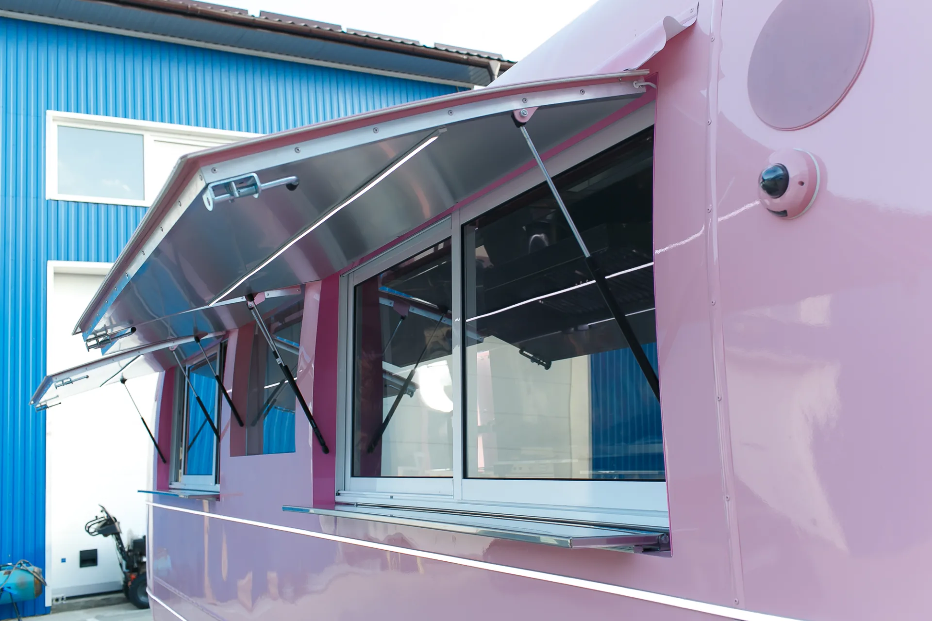 Open awning and gas struts above the service windows of a pink MobiEdge 8VT