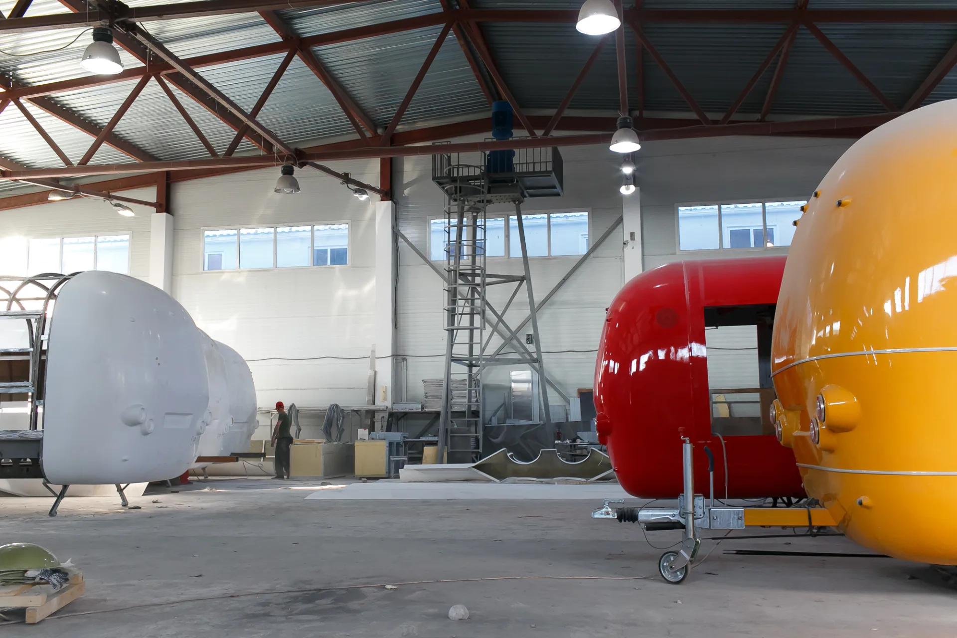 Several rounded mobile trailer shells at different build stages inside the MOBITRUCK factory