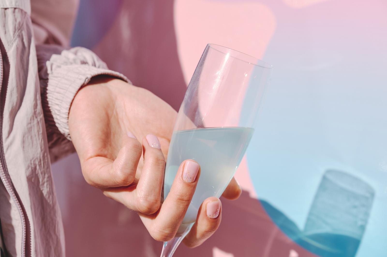 Client holding a welcome drink beside the pink MobiBeauty studio