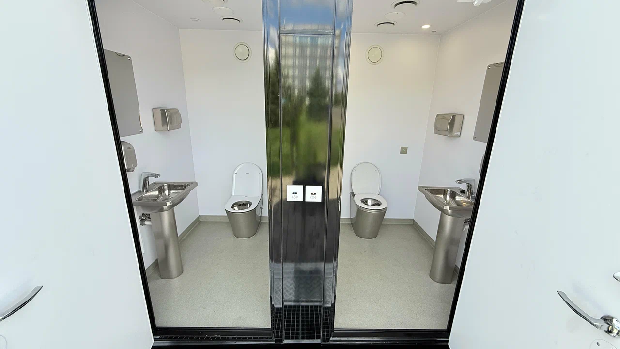Two private mobile restroom suites with stainless sinks and toilets