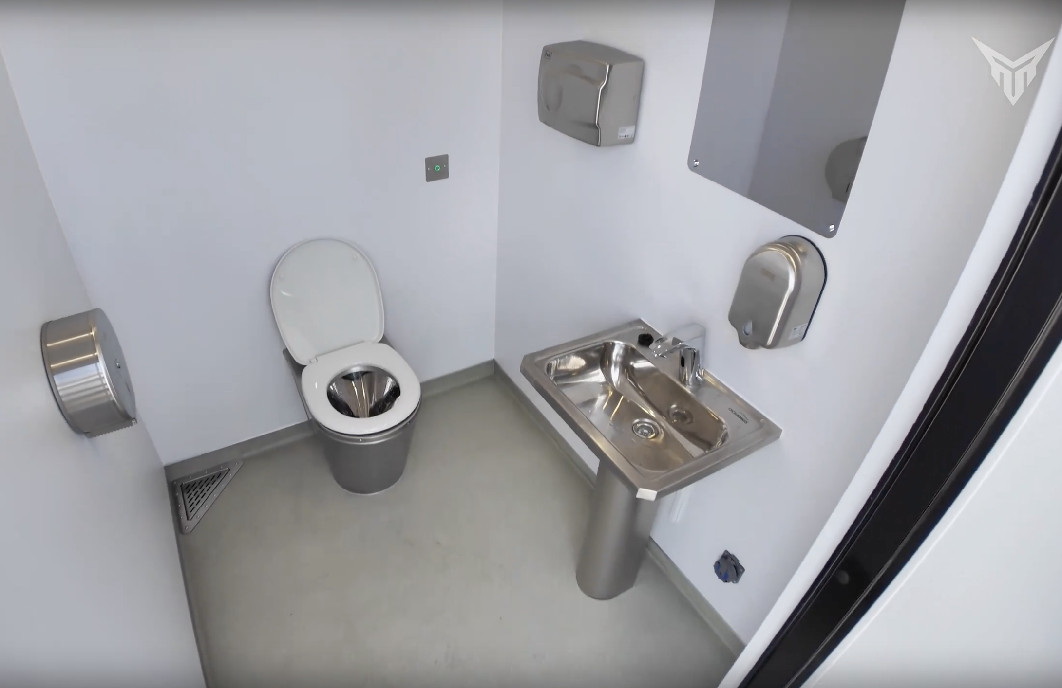 MobiRestroom interior with toilet, stainless-steel hand-washing station, mirror and accessories