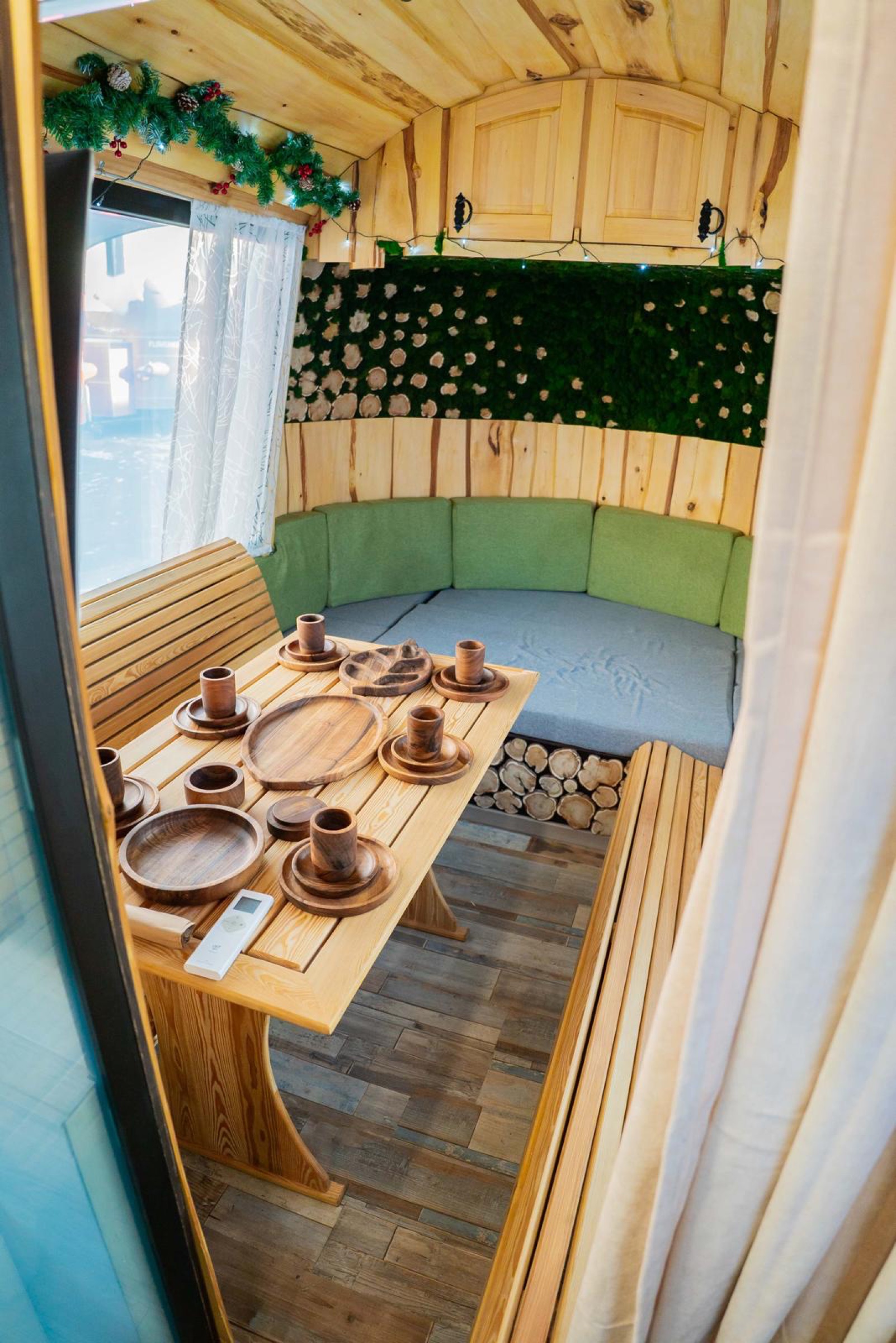Wood-lined MobiSauna lounge with table seating and moss wall details