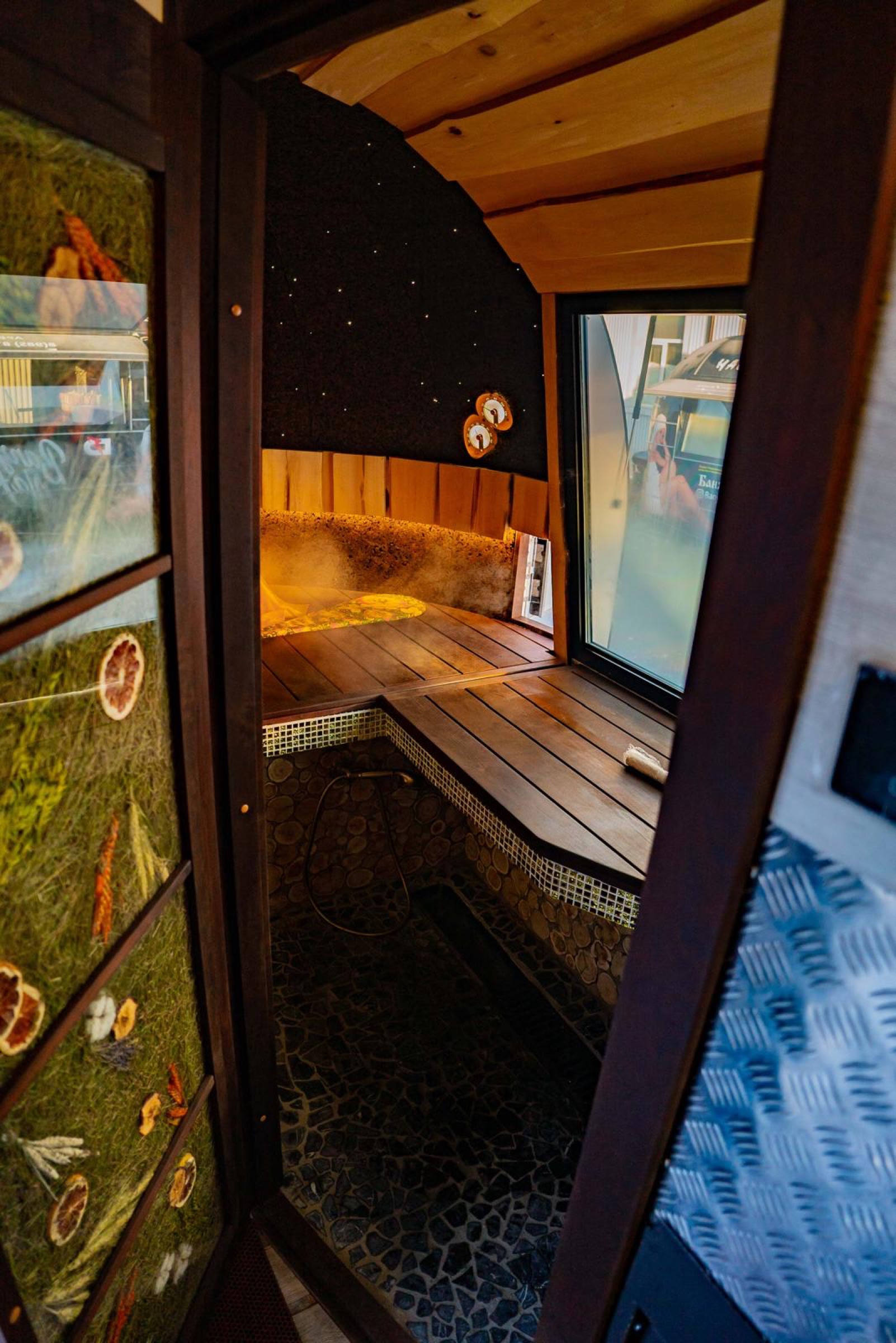 Warm MobiSauna hot room with tiered wood benches, stone details and temperature gauges